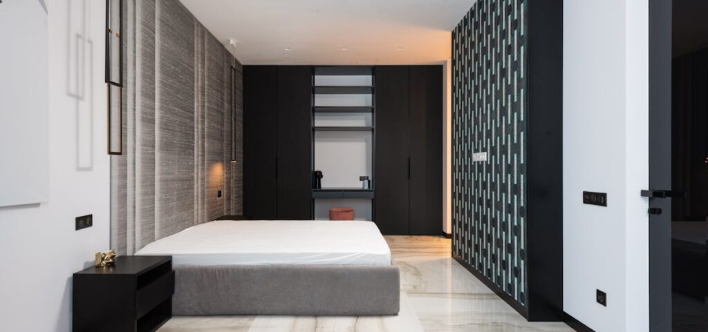 Interior of contemporary bedroom with mattress on bed near table and cabinet with decorative objects