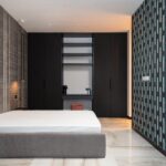 Interior of contemporary bedroom with mattress on bed near table and cabinet with decorative objects